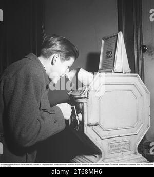 Young man at a Mutoscope, eine frühe Filmregie, die 1894 in Amerika erfunden wurde und durch Drehen nach vorne scrollen, um die Illusion von bewegten Bildern zu erzeugen. Das Mutoskop funktioniert nach dem gleichen Prinzip wie das Flipbook. Technisch funktionierte das Gerät so, dass die Bilder auf einer rotierenden Trommel sitzen und mit ca. 16 Bildern pro Sekunde angezeigt werden. Die Mutoskope sind münzbetrieben und für einen Cent zeigt dieses Mutoskop: Zelt Circus oder Intermezzo in Trikots. Schweden 1950. Kristoffersson BB43-5 Stockfoto