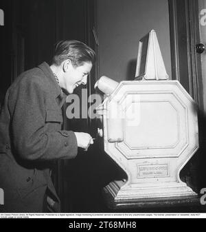 Young man at a Mutoscope, eine frühe Filmregie, die 1894 in Amerika erfunden wurde und durch Drehen nach vorne scrollen, um die Illusion von bewegten Bildern zu erzeugen. Das Mutoskop funktioniert nach dem gleichen Prinzip wie das Flipbook. Technisch funktionierte das Gerät so, dass die Bilder auf einer rotierenden Trommel sitzen und mit ca. 16 Bildern pro Sekunde angezeigt werden. Die Mutoskope sind münzbetrieben und für einen Cent zeigt dieses Mutoskop: Zelt Circus oder Intermezzo in Trikots. Schweden 1950. Kristoffersson BB43-4 Stockfoto