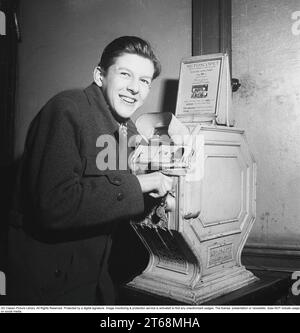 Young man at a Mutoscope, eine frühe Filmregie, die 1894 in Amerika erfunden wurde und durch Drehen nach vorne scrollen, um die Illusion von bewegten Bildern zu erzeugen. Das Mutoskop funktioniert nach dem gleichen Prinzip wie das Flipbook. Technisch funktionierte das Gerät so, dass die Bilder auf einer rotierenden Trommel sitzen und mit ca. 16 Bildern pro Sekunde angezeigt werden. Die Mutoskope sind münzbetrieben und für einen Cent zeigt dieses Mutoskop: Zelt Circus oder Intermezzo in Trikots. Schweden 1950. Kristoffersson BB43-7 Stockfoto