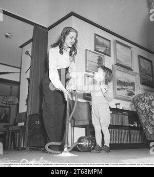 Saugen in den 1940er Jahren Eine Frau in ihrem Haus saugt zusammen mit ihrer Tochter das Wohnzimmer ab, die auch helfen will. Schweden 1947. Kristoffersson Ref. AB11-4 Stockfoto