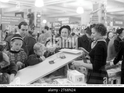 Spielzeug in den 1950er Jahren Innenausstattung aus dem NK-Kaufhaus in Stockholm. Ein Angestellter in der Spielwarenabteilung zeigt, wie die Walking Spring funktioniert. Ein klassisches Spielzeug aus dieser Zeit. Die Quelle begann beispielsweise auf einer Treppe und wanderte dann von selbst herunter. Die Kinder und Erwachsenen versammelten sich faszinierend um die Vorführuhr. Stockholm 1953. Kristoffersson Ref. 1-2 Stockfoto