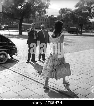 Junge Frau 1956. Sie spaziert auf Strandvägen im Zentrum Stockholms und zieht die Augen zweier Männer an, die anhalten und sie anschauen, während sie an ihnen vorbeigeht. Ein Volvo PV parkt auf der Straße. Schweden 1956. Kristoffersson Ref. BS93-8 Stockfoto