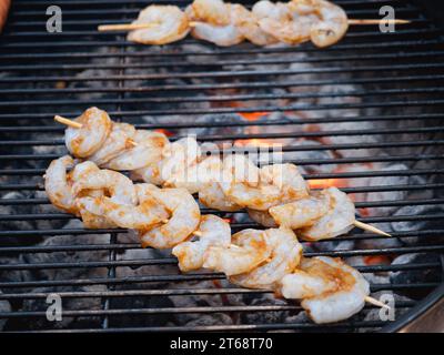 Eine Vielzahl köstlicher Speisen wird beim Kochen auf einem Grill gezeigt, einschließlich Garnelen und Garnelen-Kebabs Stockfoto