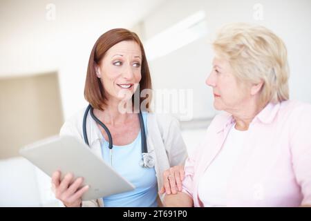 Sicherheit in schwierigen Zeiten - Seniorengesundheit. Reife Krankenschwester erklärt das Ergebnis ihrer älteren Patienten medizinischen Tests. Stockfoto