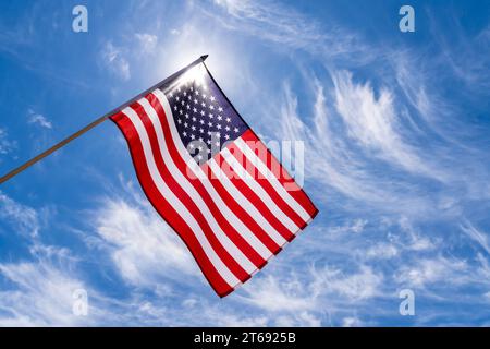 Amerikanische Flagge winkt in einem blauen Himmel mit gestreiften Wolken Hintergrund. Der rote, weiße und blaue Stern gestreift die USA, die US-Flagge weht hoch. Stockfoto