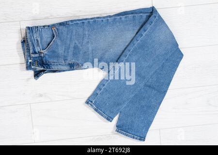 Blaue Jeans gefaltet auf weißem hölzernem Hintergrund, Denim gefaltet auf hellem hölzernem Hintergrund - Draufsicht Stockfoto