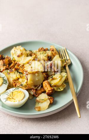 Köstliche herzhafte Abendessen oder Mittagessen, gebratene junge Kartoffeln mit Waldpilzen Chanterelles mit Dill, gekochte Eier, saisonale Speisen Stockfoto