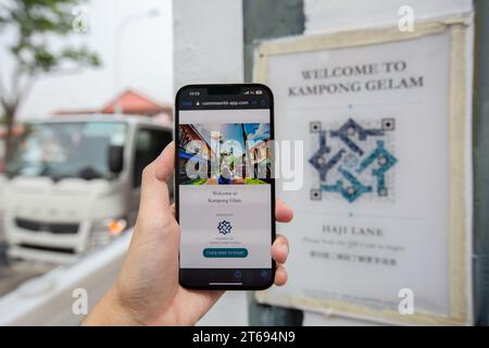 Die linke Hand hält das iPhone 13, um den QR-Code zu scannen, Erkundungen, Besichtigungen und informative Reisen in Kampong Gelam, Haji Lane zu beginnen. Singapur. Stockfoto