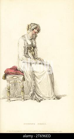 Regency Frau im Morgenkleid auf einem Stuhl sitzend. Robe aus einfachem Jaconot-Musselin mit spencer Mieder, lockerer Robenpelisse aus indischem Musselin, Flushing Mob Cap aus Spitze, bernsteinfarbenem Rosenkranz und Kreuz, Zitrone-Kinderschuhen und Handschuhen. Plate 5, Vol. 11, Januar 1 1814. Handkolorierter Kupferstich aus Rudolph Ackermanns Repository of Arts, London. Stockfoto