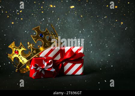 Krone der drei Weisen mit Weihnachtsgeschenkboxen und weihnachtslichtern auf grauem Hintergrund. Konzept für den Tag Dia de Reyes Magos. Drei Kluge Männer Stockfoto