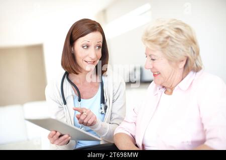 Herzlichen Glückwunsch, dass Sie ganz klar sind. Die reife Krankenschwester gibt ihrem älteren Rollstuhlpatienten die gute Nachricht. Stockfoto