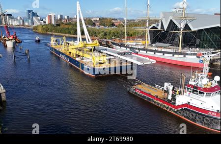 Drei Schiffe, die vor einem großen, durch die Wolken schrafenden Gebäude segeln, bieten einen spektakulären Blick auf die Skyline der Stadt Stockfoto