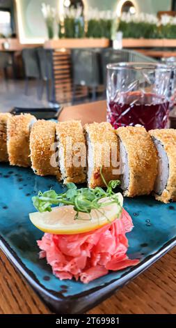 Sushi-Sets, Brötchen mit Kaviar, Garnelen, Thunfisch, Avocado und Philadelphia-Käse auf einem farbigen Teller in einem Fast-Food-Restaurant. Kopierbereich Stockfoto