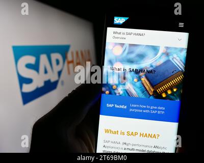 Person, die ein Mobiltelefon hält und die Webseite der Datenbank-Management-Software SAP HANA vor dem Geschäftslogo zeigt. Konzentrieren Sie sich auf die Mitte des Telefondisplays. Stockfoto