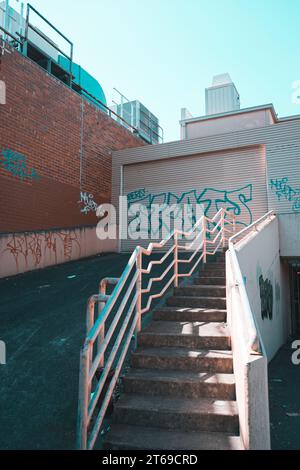 Eine architektonische Struktur mit einer Treppe, die zu einem Gebäude führt, das mit farbenfrohen Graffiti-Kunstwerken geschmückt ist Stockfoto