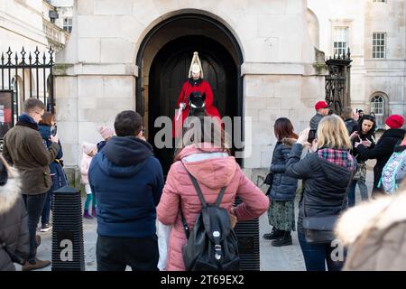 Ein Soldat des Household Cavalry Mounted Regiment sitzt auf seinem Pferd im Dienst vor einer Gruppe von Touristen bei Horse Guards in London Stockfoto