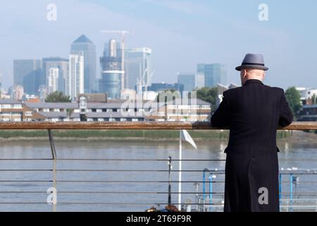 Ein Mann blickt über die Themse in Greenwich, London, auf die Wolkenkratzer der Docklands Stockfoto