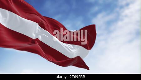 Nationalflagge der Republik Lettland winkt an einem klaren Tag im Wind. Rotes Feld mit einer weißen horizontalen Linie in der Mitte. 3D-Darstellung. Ripp Stockfoto