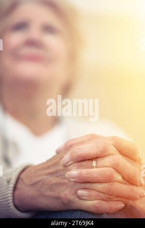 Anmutig altern ist eine Tugend. Eine ältere Frau hat die Hände auf ihrem Schoß zusammengelegt. Stockfoto