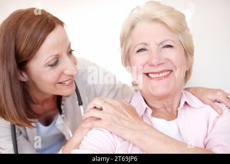 Eine starke Verbundenheit zwischen Arzt und Patient - Seniorenbetreuung. Nahaufnahme-Porträt einer Reifen Krankenschwester und ihrer älteren Patientin, die einen liebevollen Moment teilen Stockfoto