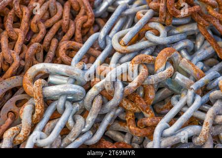 Nahaufnahme eines großen Haufens über große Kettenglieder, die aufgrund chemischer Reaktionen bei Witterungseinwirkung rostig und gekröpft sind Stockfoto