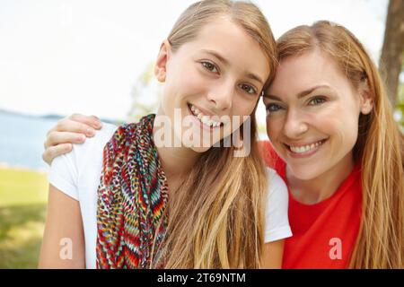 Zwei Erbsen in einer Schote. Lächelnde Mutter und Tochter umarmen sich im Freien. Stockfoto