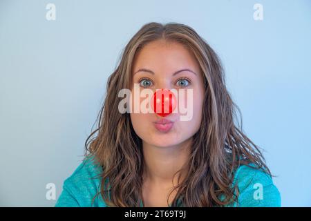 Porträt einer jungen Frau mit Clownnase und vor der Kamera. Ansicht schließen. Stockfoto