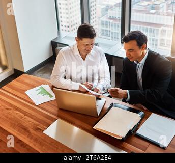 Jede Information ist wichtig. Zwei Geschäftsmänner, die ein Gespräch führen, während sie an einem Laptop sitzen. Stockfoto