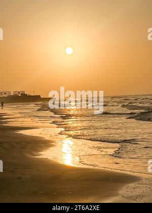 Eine fröhliche Gruppe von Surfern, die an der Sandküste eines Strandes spazieren Stockfoto