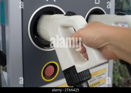 Nahaufnahme des Fahrers, der das Fahrzeug auflädt, während die Hand den Stecker hält. Nachhaltiges Energiekonzept. Stockfoto