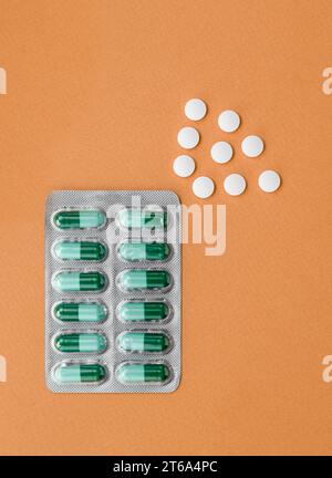 Verschiedene medizinische Pillen auf orangefarbenem Hintergrund. Tabletten gegen Schlaflosigkeit. Selbstversorgung, guter Schlaf, Schlaflosigkeit. Stockfoto