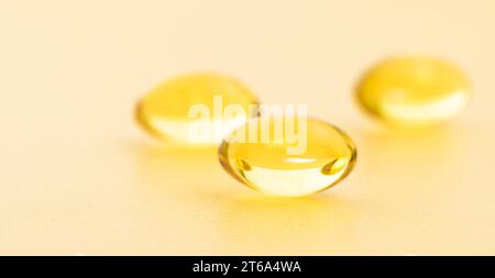 Fischöl-Ergänzungskapseln auf Goldgrund. Kosmetik, Omega 3 goldene Blase. Goldölkapseln. Vitamin-Rundpillen-Set. Stockfoto