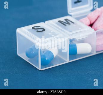 Organisator für Pillen, Vitamine und Nahrungsergänzungsmittel auf hellblauem Hintergrund. Pflegekonzept Stockfoto