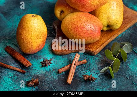 Birnen auf dunklem Hintergrund. Frische, reife Früchte auf blauem Teller und in einer Schachtel. Gesunde Ernährung. Kopierbereich. Stockfoto