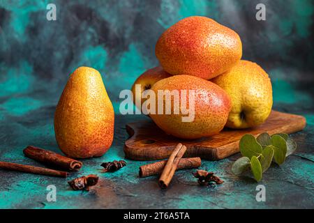Birnen auf dunklem Hintergrund. Frische, reife Früchte auf blauem Teller und in einer Schachtel. Gesunde Ernährung. Kopierbereich. Stockfoto