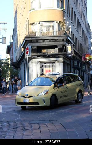 Ein gelbes Taxi steht auf einer belebten Straße, in der sich andere Fahrzeuge und Fußgänger bewegen Stockfoto