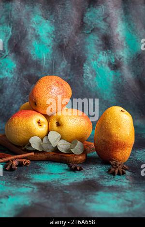 Birnen auf dunklem Hintergrund. Frische, reife Früchte auf blauem Teller und in einer Schachtel. Gesunde Ernährung. Kopierbereich. Stockfoto