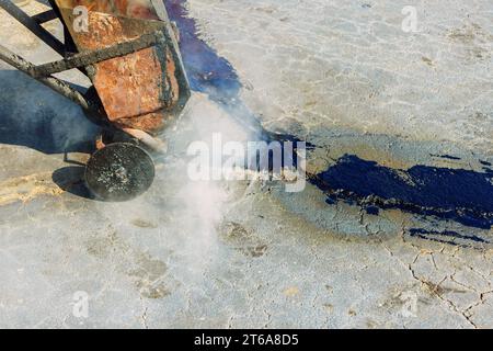 Fugendichtungseinfüllflüssigkeit zur Reparatur von Rissen im Asphalt mit Bitumenemulsion Fugendichtungsrestaurierer zur Wiederherstellung der Straßenoberfläche. Stockfoto