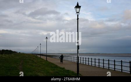 Die Abenddämmerung und ein einsamer Radfahrer radeln entlang der Promenade in Lytham St Annes, Lancashire, Großbritannien, Europa Stockfoto