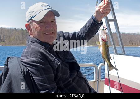 Stolzer Angler, der einen möglichen großen Maulbarsch auf dem Gull Lake Angelöffner zeigte, kehrte zum Wasser zurück, um aufzuwachsen. Nisswa Minnesota MN USA Stockfoto