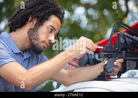 Junger Mann, der etwas auf dem Autodach installiert Stockfoto