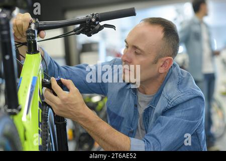 Der Mann überprüft das Fahrrad, bevor er im Geschäft kauft Stockfoto