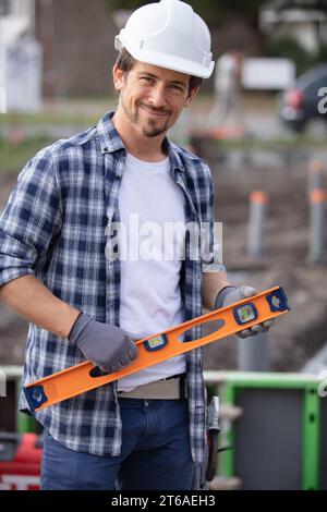 Glücklicher Mann, der auf der Baustelle den Holzstand überprüft Stockfoto