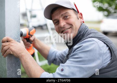 Mann, der einen elektrischen Schraubendreher benutzt, um eine Metallstange zu bohren Stockfoto