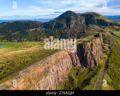 Luftaufnahme der Salisbury Crags mit Arthurs Sitz nach hinten im Holyrood Park, Edinburgh, Schottland, Großbritannien Stockfoto