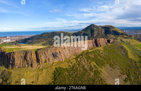 Luftaufnahme der Salisbury Crags mit Arthurs Sitz nach hinten im Holyrood Park, Edinburgh, Schottland, Großbritannien Stockfoto