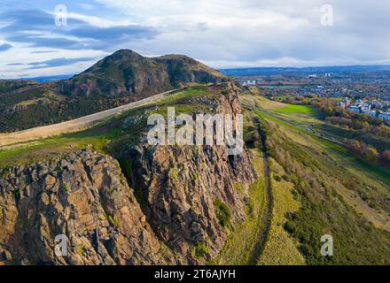 Luftaufnahme der Salisbury Crags mit Arthurs Sitz nach hinten im Holyrood Park, Edinburgh, Schottland, Großbritannien Stockfoto