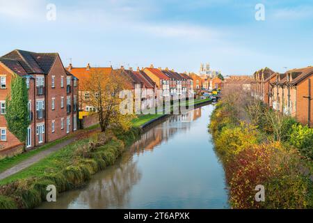 Der Beck, Kanal, flankiert von Stadthäusern mit Blick auf das alte Münster am Horizont unter bewölktem blauen Himmel an einem schönen Herbstabend in Beverley, Großbritannien. Stockfoto