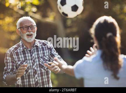 Senior-Mann und junge Krankenschwester spielen Fußball im Park Stockfoto