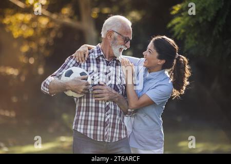 Senior-Mann und junge Krankenschwester spielen mit Ball im Park Stockfoto